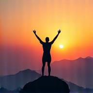 Athlete raising arms in victory on a mountain peak at sunset, symbolizing peak performance and thriving.